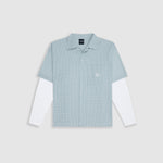 Checkered double sleeve shirt with light green, blue, and white plaid body, off-white contrast sleeves, boxy fit, and embroidered monogram on the chest pocket.