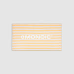 Monoic cotton towel with white background, bold yellow stripes, and “Monoic” written horizontally.