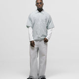Checkered double sleeve shirt with light green, blue, and white plaid body, off-white contrast sleeves, boxy fit, and embroidered monogram on the chest pocket.