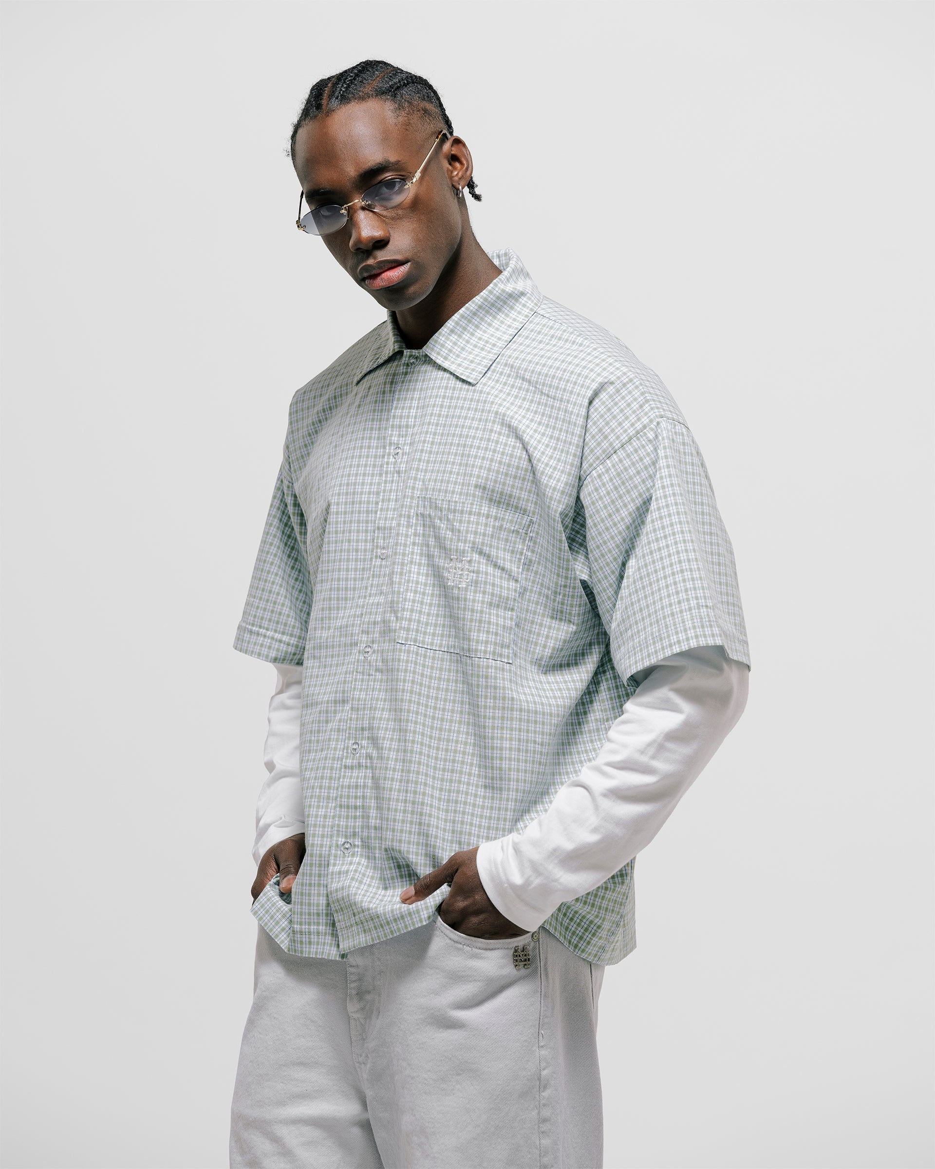 Checkered double sleeve shirt with light green, blue, and white plaid body, off-white contrast sleeves, boxy fit, and embroidered monogram on the chest pocket.