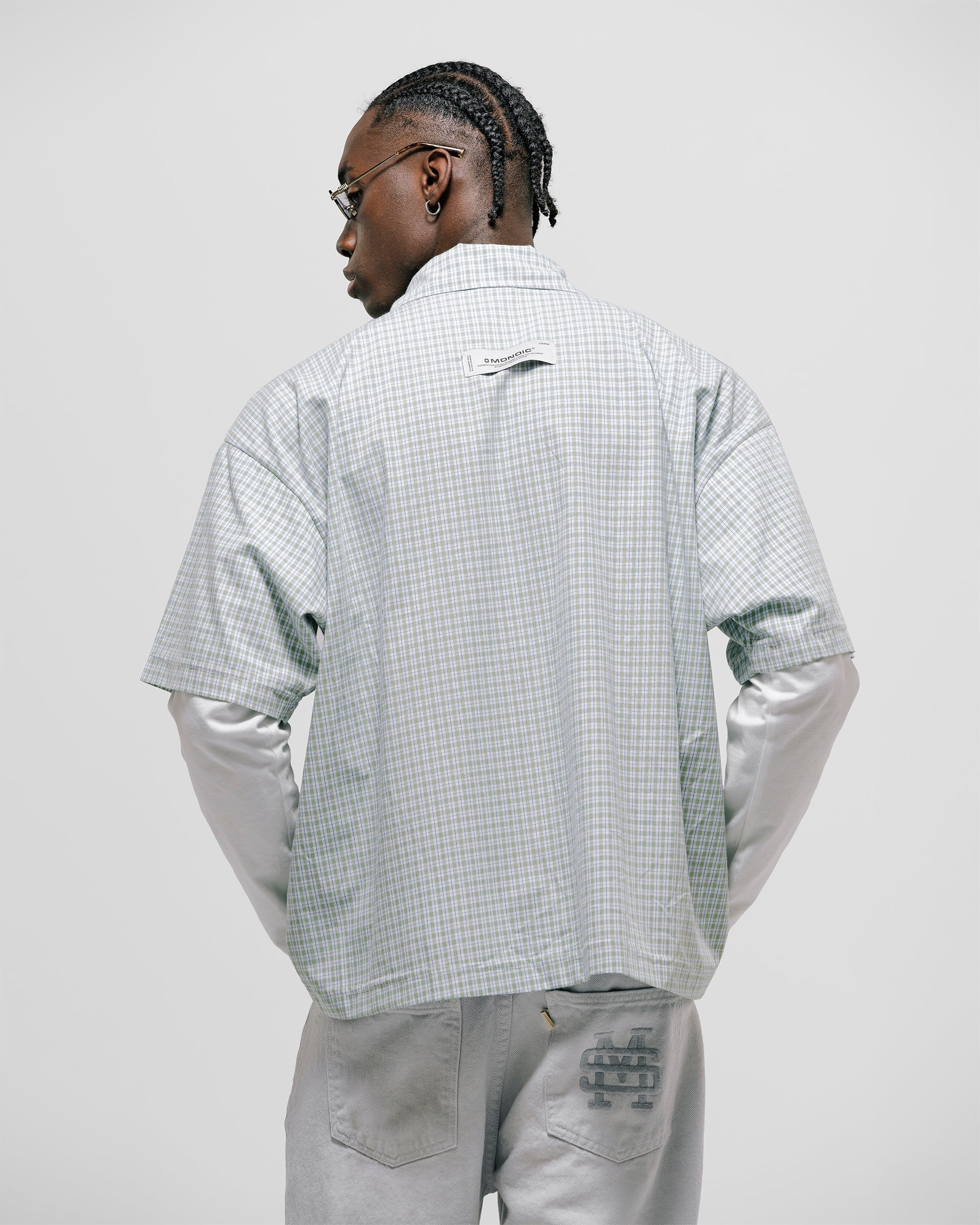 Checkered double sleeve shirt with light green, blue, and white plaid body, off-white contrast sleeves, boxy fit, and embroidered monogram on the chest pocket.
